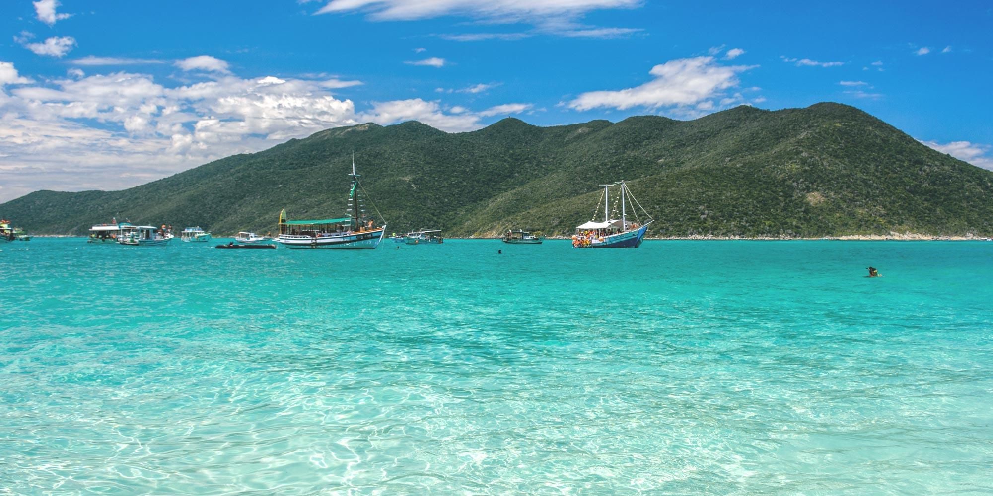 Mar de águas cristalinas e barcos em Arraial do Cabo