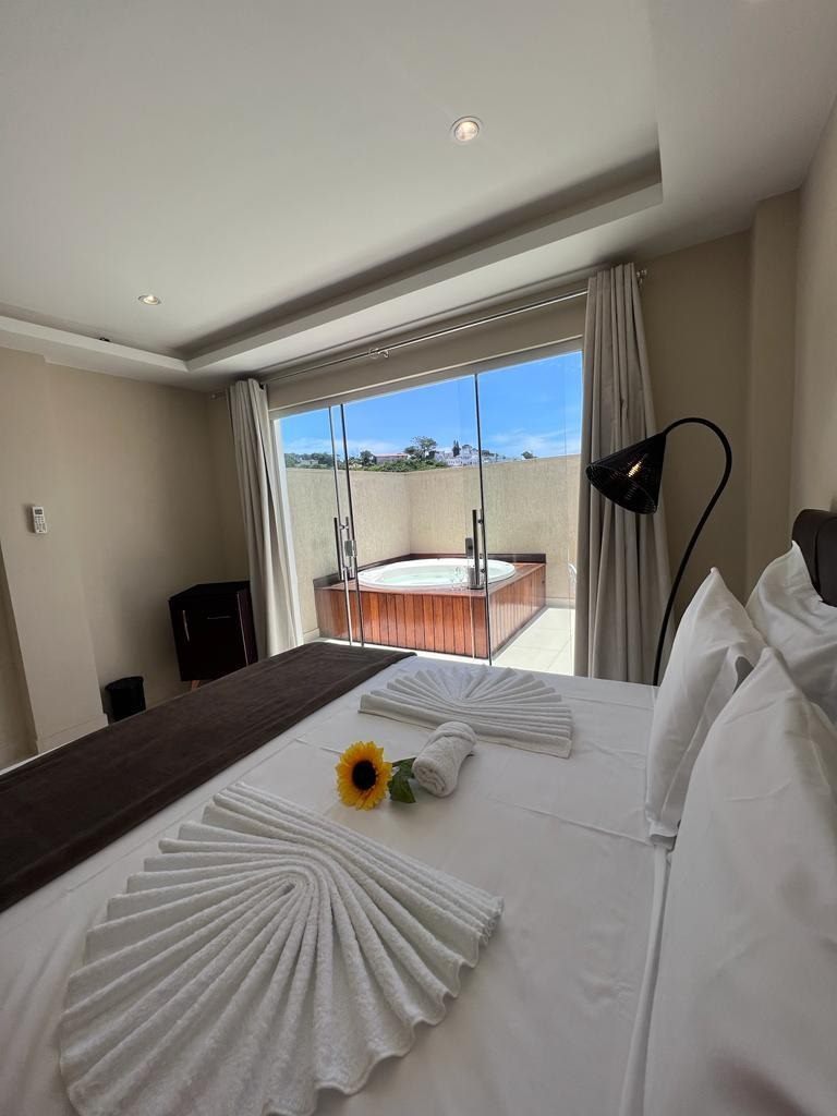 Suíte com Hidromassagem, cama arrumada com girassol e vista da varanda